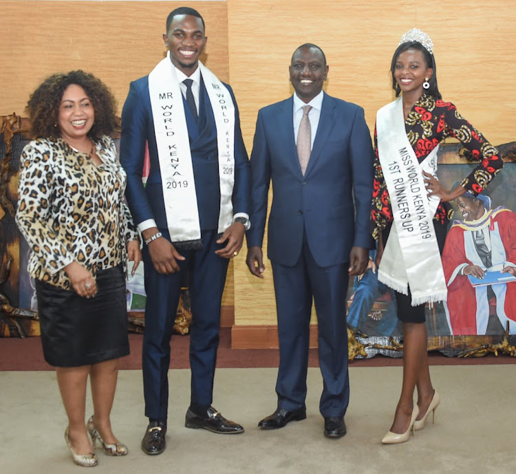 Deputy President William Ruto presents flags to Mr World Kenya 2019, Franklyne Asoyo and Miss World Kenya 1st runners up, Elsie Hemsi Stephens.