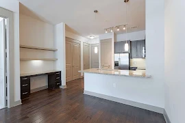 Kitchen with dark wood cabinets, stainless steel appliances, granite countertops, dark wood floors, built in desk with shelves