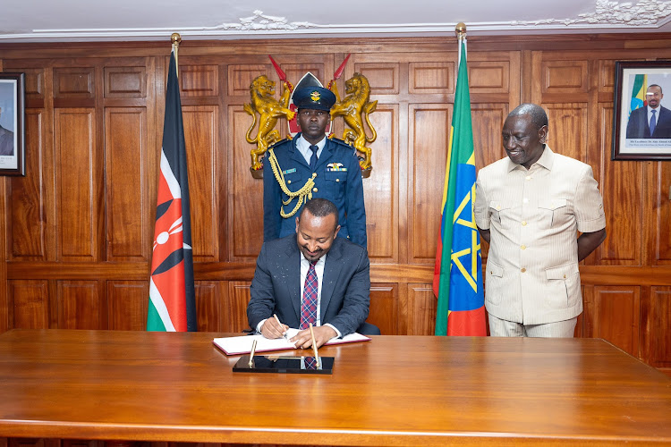 Ethiopia Prime Minister Abiy Ahmed signing a visitor's book as President William Ruto looks on at the Jomo Kenyatta International Airport on February 27, 2024.