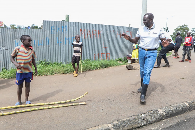 President William Ruto buying sugarcane from a school boy to promote him when he visited Mathare to assess flood situation on May 6, 2024.