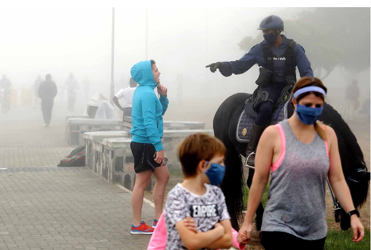 Law enforcement officers confront a jogger about not wearing a mask.