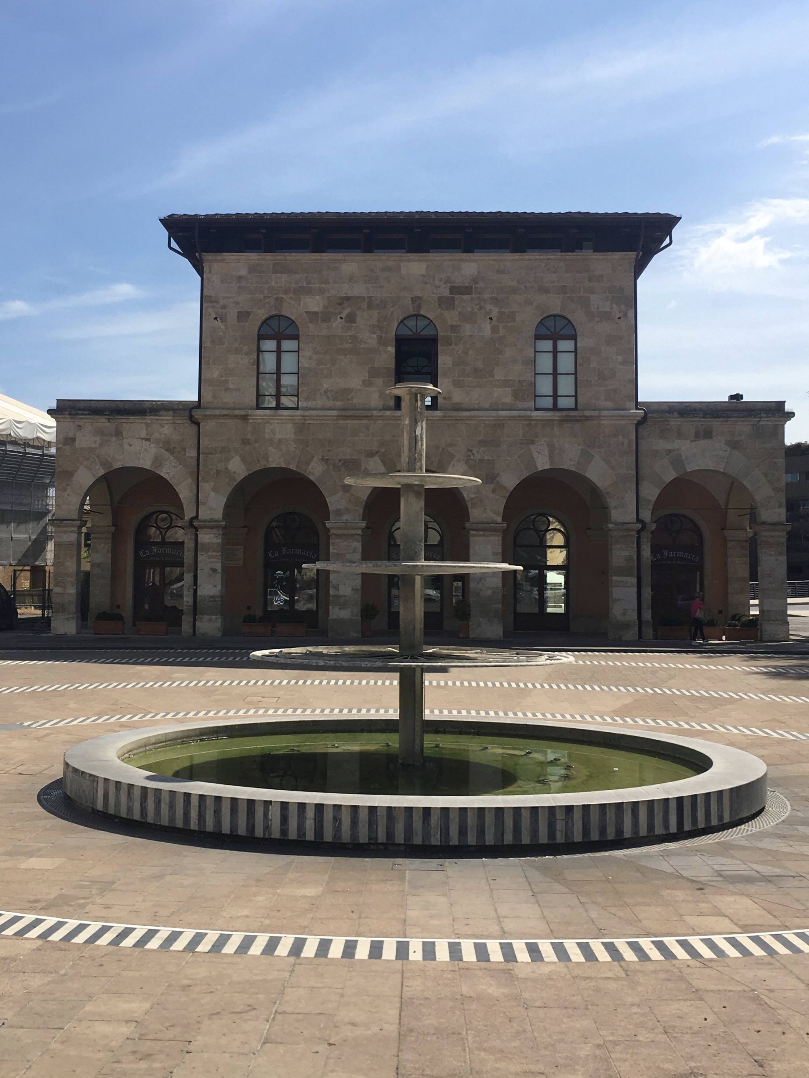 Colle Val d'Elsa, Piazza Arnolfo di Cambio, il lato della vecchia stazione ferroviaria, nel centro una moderna e singolare fontana