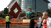 People walk past a floral installation featuring a medical worker in the fight against the coronavirus disease, set up ahead of Chinese National Day on October 1, on Changan Avenue in Beijing, China on September 25, 2020.
