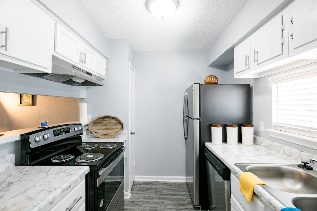 Kitchen with white cabinets, stainless steel appliances, and wood-inspired flooring