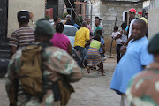 Residents of Alexandra watch as soldiers move through the area. File photo.
