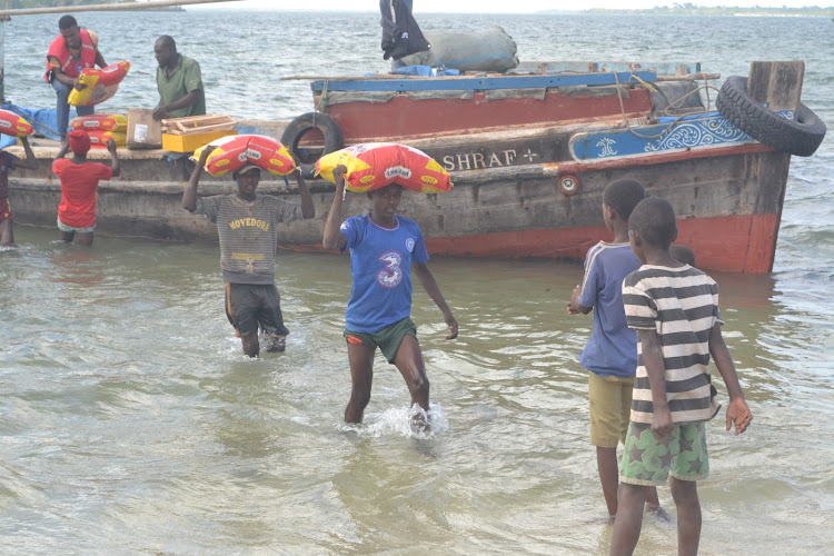 Youth from Kiangwe village help offload relief food donated by Kenya Red Cross Society