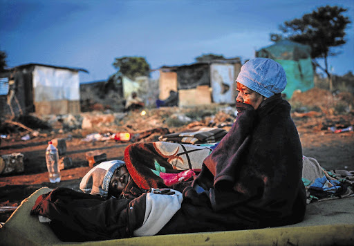 OUT IN THE COLD: A 62-year-old woman tries to keep warm on Saturday night after her shack at Nellmapius, east of Pretoria, was demolished. Known as 'Malemaville', the settlement was established illegally on council-owned land by Economic Freedom Front activists. File photo