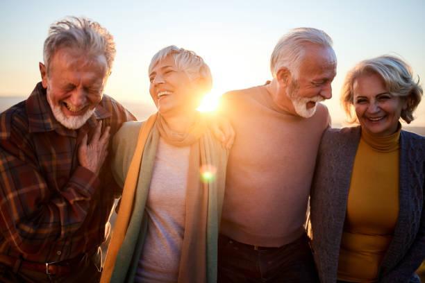 Happy mature couples talking while walking in autumn day. Happy senior couples communicating while walking in autumn at sunset. empty nester stock pictures, royalty-free photos & images