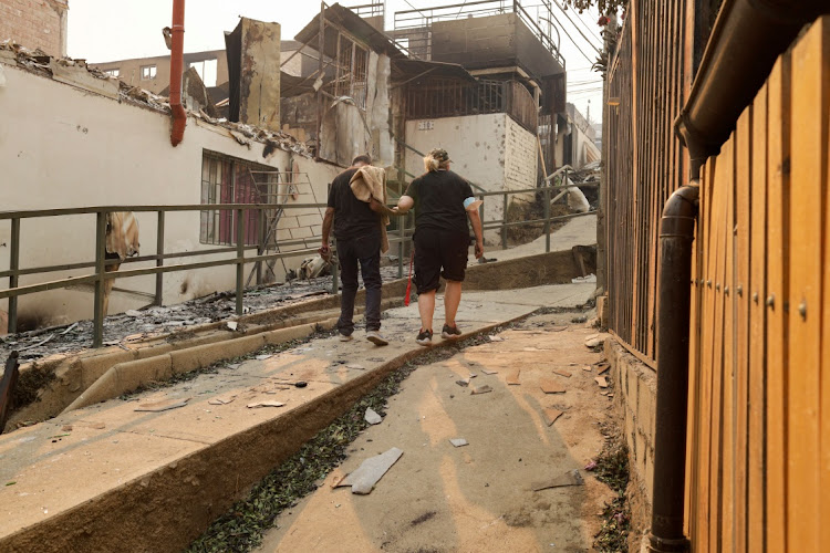 A couple walks around the remains of burnt houses looking for their missing pets, following the spread of wildfires in Vina del Mar, Chile February 3 2024. Picture: SOFIA YANJARI/REUTERS