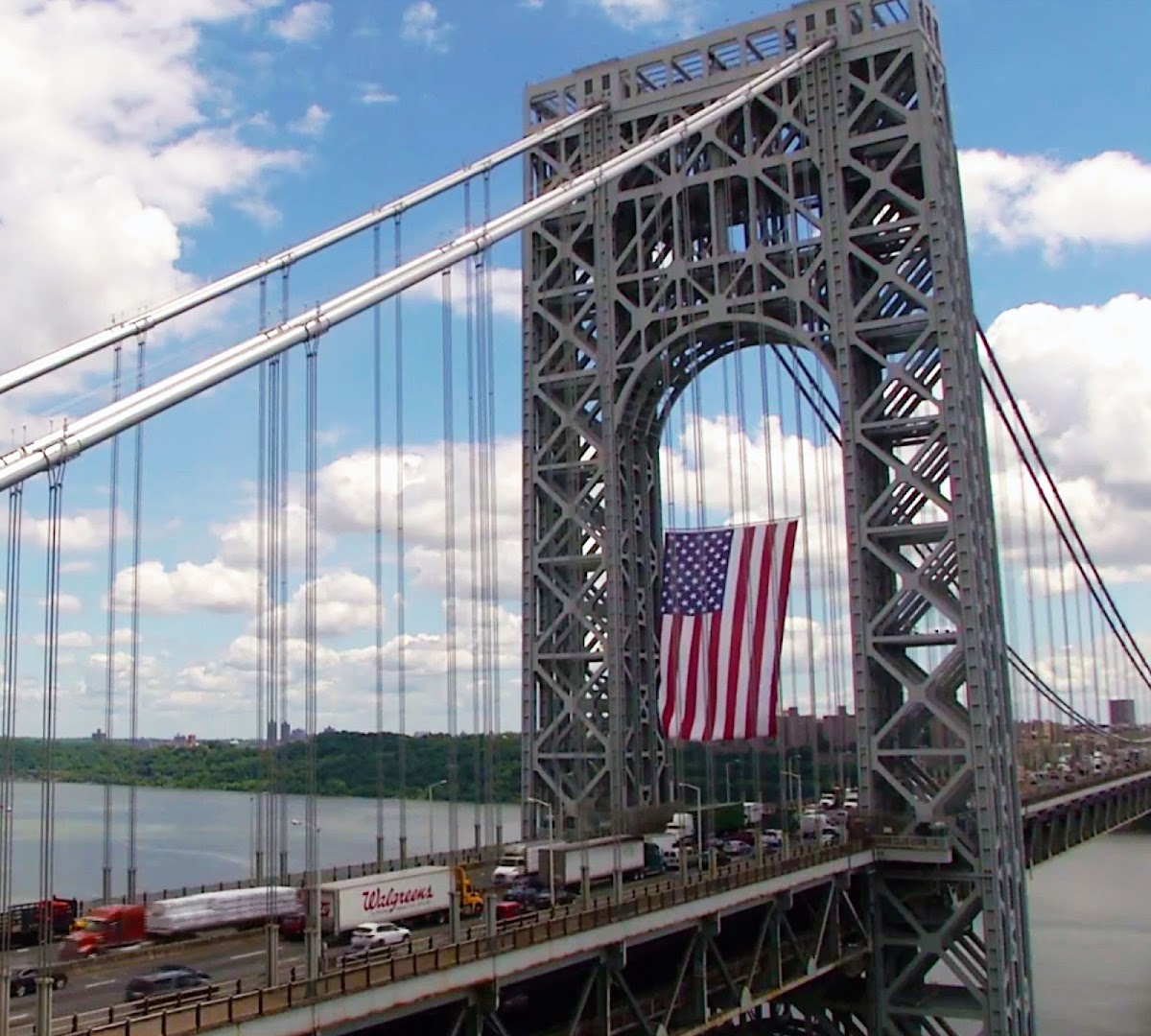 An American flag hanging from a suspension bridge tower