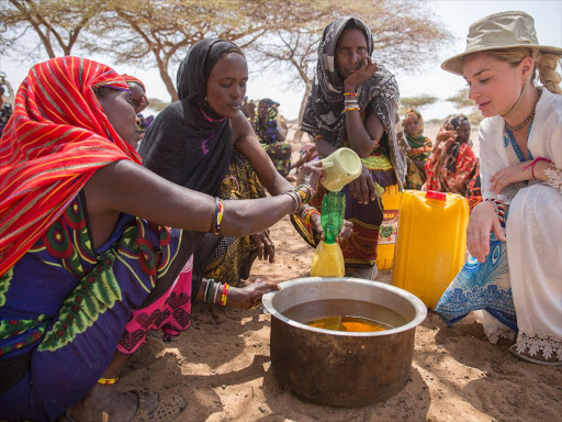 Emma Rigby divides cooking oil with women in Bubisa, Marsabit county / COURTESY