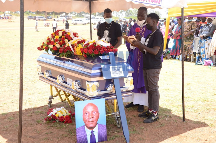 Priest reads prayers during the burial during the burial of their dad at Langata Cemetery,