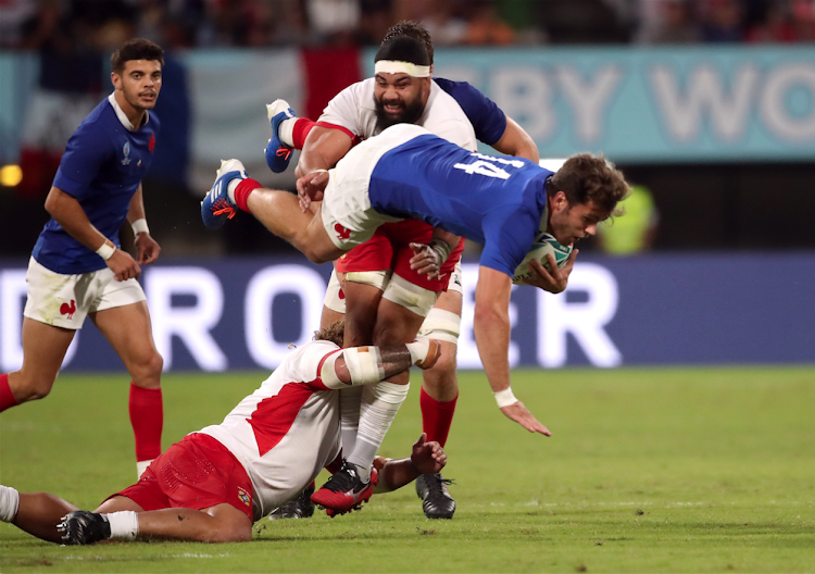 France's Damian Penaud evades a tackle from Tonga's Siosiua Halanukonuka and Maama Vaipulu