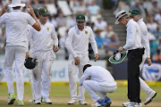 Dean Elgar of South Africa takes a closer look as injured Keshav Maharaj of South Africa crouch during day 2 of the 3rd Sunfoil Test match between South Africa and Australia at PPC Newlands on March 23, 2018 in Cape Town, South Africa. 