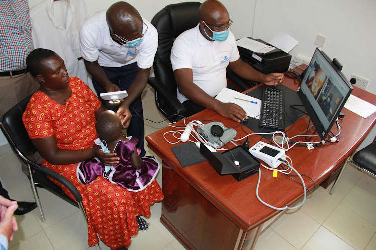 Getrude's hospital Foundation clinical officers Mark Mochacha and Maurice Ogalo diagnose a child during the launch of the telemedicine centre at Suba Subcounty hospital in Homa Bay on November 26.