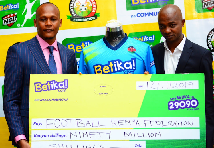 Betika's head of commercial John Mbatiah (L)presents a cheque to FKF's Nick Mwendwa during a press conference at a Nairobi Hotel on November 12,2019