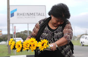 Jacoba Mouton, who worked at Denel for 22 years, lays flowers in front of the munitions plant. 