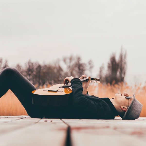 Hombre acostada, relajado y tocando la guitarra