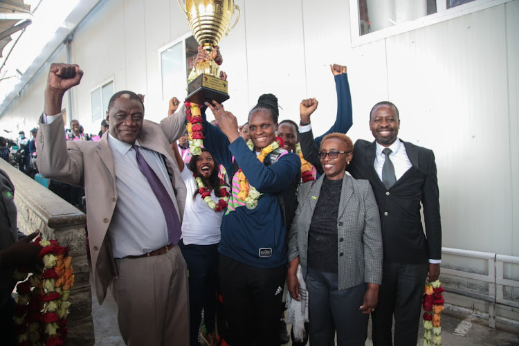 KVF deputy president Charles Nyaberi lifts the trophy with KCB captain Edith Wisa at KENCOM house, Nairobi