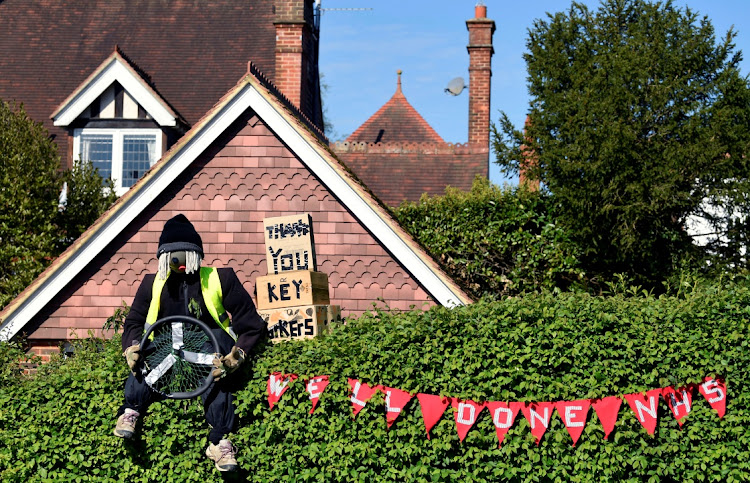 A figure representing an essential services worker is seen in a front garden in the village of Capel, outside London, on Sunday