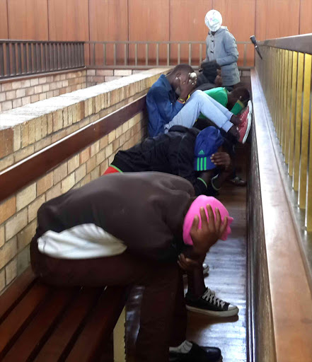 IN THE DOCK: Suspects seek to avoid having their photograph taken by the Daily Dispatch as they wait for court proceedings to resume yesterday Picture: MAMELA GOWA