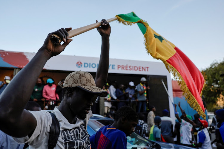 A supporter of the detained presidential election candidate Bassirou Diomaye Faye holds the country's flag during an electoral caravan to support Faye, in the outskirts of Dakar, Senegal, March 12 2024. Picture: REUTERS/Zohra Bensemra