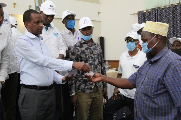 Mandera East MP Omar Salah hands an NHIF card to a resident during a ceremony at Granada Hotel on Monday, September 21, 2020