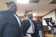 Former Tshwane mayor Murunwa Makwarela, left, walks out of the Pretoria specialised commercial crimes court on Tuesday after the matter was postponed due to him failing to brief his legal team ahead of the court date. 