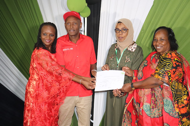 Taita Taveta Governor Granton Samboja, his wife Stella and running mate Priscilla Mwangeka receives a clearance certificate from the IEBC County elections manager Eisha Mohamed on Monday.