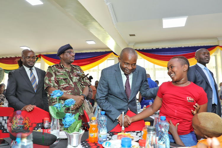 Interior CS Kithure Kindiki having a light moment with kids during a memorial service at Embakasi AP training College, Nairobi on Friday, December 16, 2022.