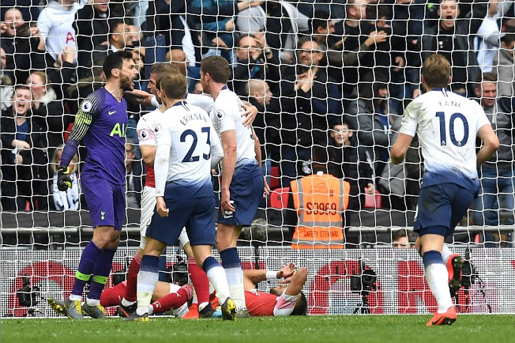 Tottenham Hotspur's Hugo Lloris, in purple, celebrates with teammates after saving a penalty whilst Pierre-Emerick Aubameyang (down on the ground) and Nacho Monreal of Arsenal look dejected during the Premier League match at Wembley Stadium on Saturday.