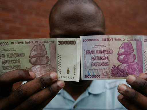 A man holds up d 200 million and 500 million Zimbabwe dollar notes in the capital Harare December 12, 2008. /REUTERS