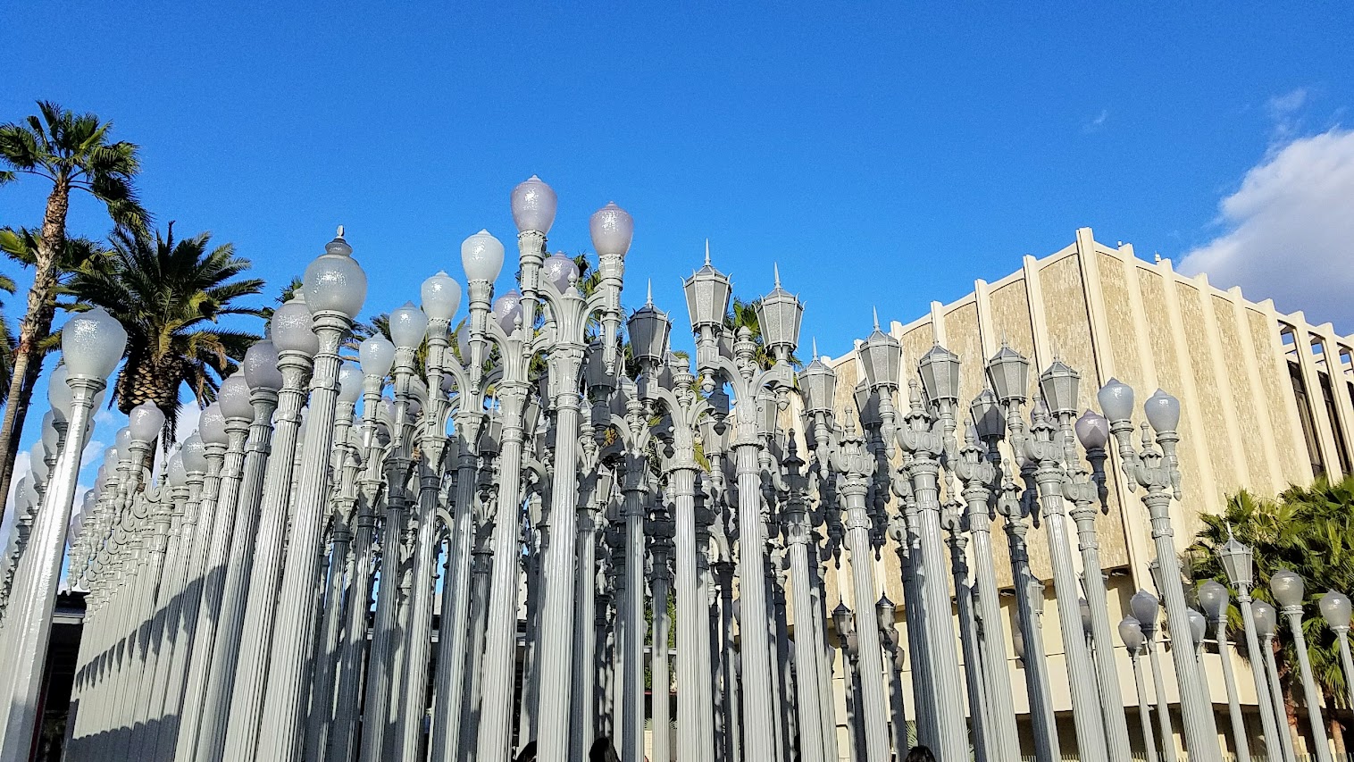 One of the most famous and free (since it is an outdoor sculpture) art you can see in the park at LACMA is the iconic Urban Lights. Created by Chris Burden, it is made of 202 restored street lamps in various styles based on where they were from (most are from southern California and some from Portland Oregon too!). The lamps are painted grey and assembled in a grid, and are solar powered and become lit in the evening.