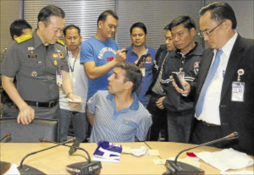 SUSPECTED BOMBER: Mohammad Hazaei, 42, seated, speaks to policemen after he was arrested at Suvarnabhumi Airport in Bangkok. Hazaei was sharing a rented house with another Iranian national who lost a leg when a bomb he was carrying went off. Photo: REUTERS