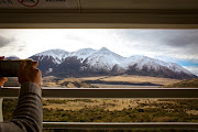 The TranzAlpine train passing snow-covered Mount Binser in Arthur's Pass National Park.