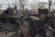 A Ukrainian serviceman walks past the wreck of a Russian tank in the village of Lukyanivka outside Kyiv, as Russia's invasion of Ukraine continues on March 27 2022. 