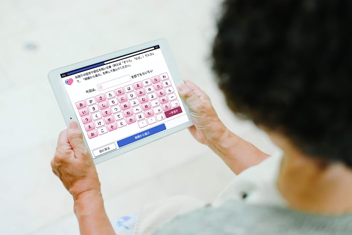 Woman sits looking at tablet with Ubie interface on it