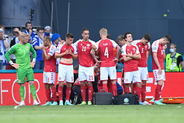 Joakim Maehle, Yussuf Poulsen, Simon Kjaer and Thomas Delaney of Denmark look dejected as team mate Christian Eriksen (hidden) receives medical treatment during the UEFA Euro 2020 Championship Group B match between Denmark and Finland on June 12, 2021 in Copenhagen, Denmark.