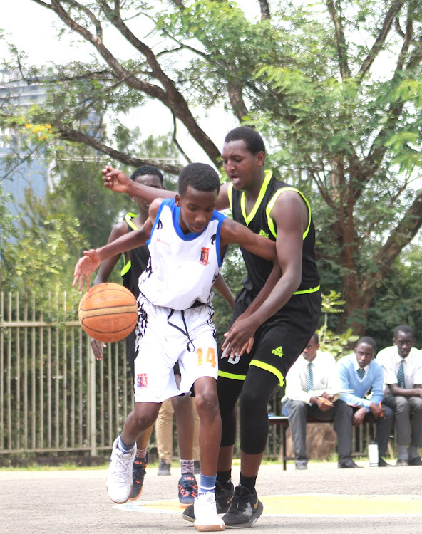 Strathmore School's Mwai Kanyi dribbles the ball as he shields away Eastleigh High School's Mohamed Ayub (L) on Friday, March 13 at State House Girls basketball courts.