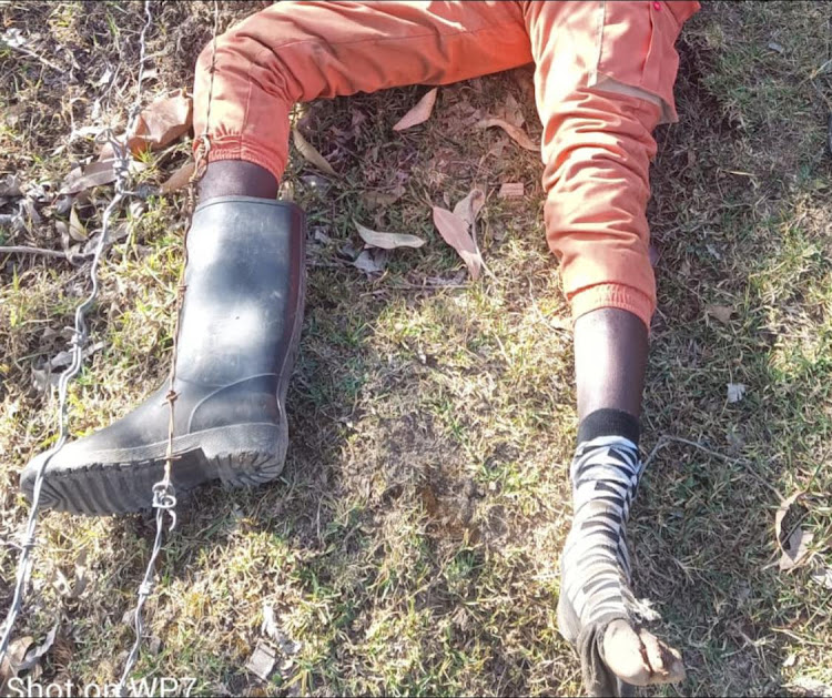 The unidentified man laying on ground without his left gumboot.