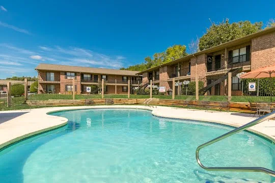 Swimming pool with lounge furniture, tables and chairs, and a sundeck next to apartment buildings