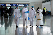 Medical workers walk by a police robot at the Wuhan Tianhe International Airport after travel restrictions were lifted, April 8, 2020. File photo 