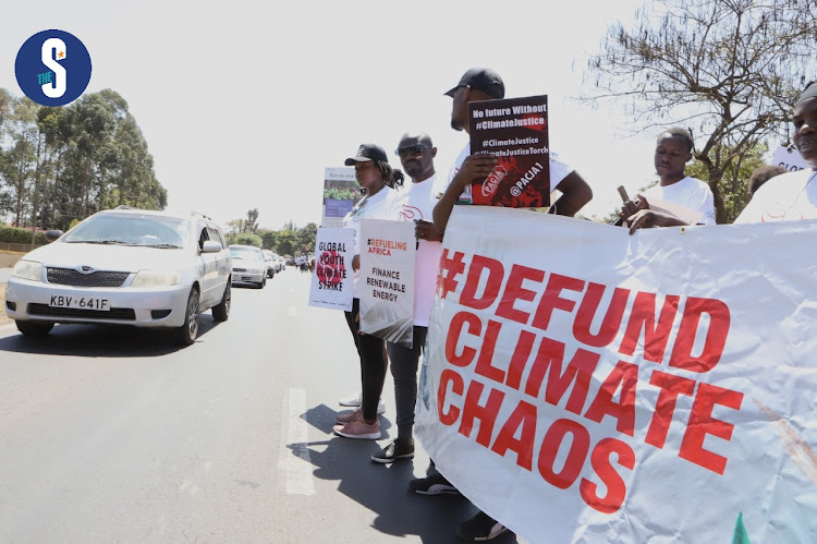 Activists, youths and NGO members carry banners to call for financing and action against loss and damage caused by climate change match along Langata Road, Nairobi on September 24, 2022.