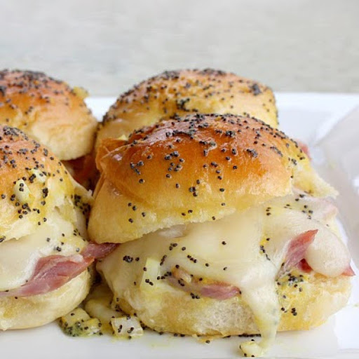 Heavenly ham and cheese sliders! A melty gooey mound of Swiss cheese on a mini stack of ham complete with a bun basted with a special surprise!