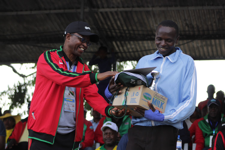 MAchakos Boys' Principal Benson Manoo presents a trophy and Brookside gift hamper to cross country Most valuable Player(MVP) Anthony Biwott.