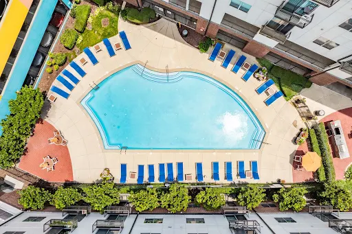 Aerial view of a curated apartment complex pool area featuring lounge chairs and landscaped surroundings.