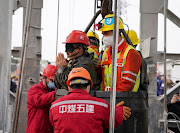 Rescue workers help a miner as he is brought to the surface at the Hushan gold mine after the January 10 explosion trapped workers underground, in Qixia, Shandong province, China January 24, 2021. 