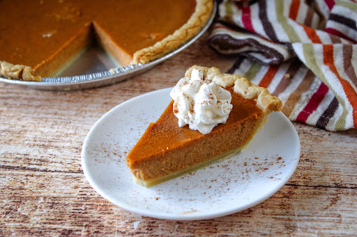 A slice of Ricotta Pumpkin Pie with whipped cream.