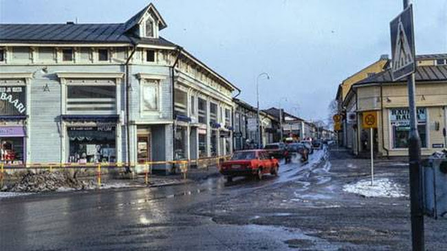 Tämä kuva kuvaa hyvin sitä, miten 1990-luvun alussa Vanhan Rauman yleisilmeeseen ei juurikaan kiinnitetty erityistä huomiota. Maailmanperintökohde-listauksen myötä myös katukuvaa haluttiin yhtenäistää ja samalla poistaa sinne kuulumattomia elementtejä. Kuvassa esimerkiksi liikennemerkit, metallikaide ja näyttävät teippaukset liikkeiden ikkunoissa.