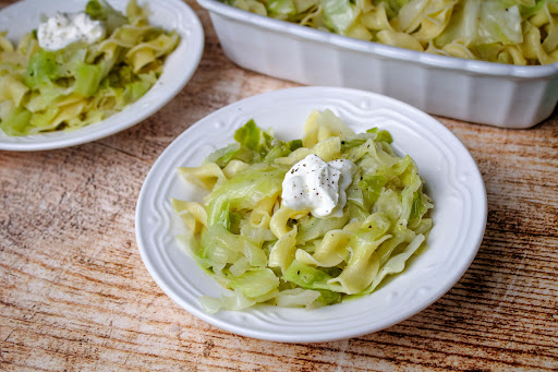 Krautfleckerl - Hungarian Cabbage and Noodles in a bowl with sour cream.